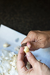 Close up of human hand peeling garlic - ABAF000275