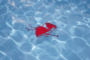 Germany, Red bikini top floating in swimming pool - JTF000010