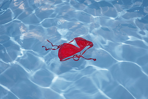 Germany, Red bikini top floating in swimming pool - JTF000010