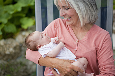 Germany, Bavaria, Woman with grandchild sitting in lawn chair, smiling - HSIYF000003