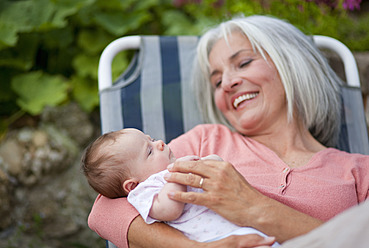 Germany, Bavaria, Woman with grandchild sitting in lawn chair, smiling - HSIYF000004