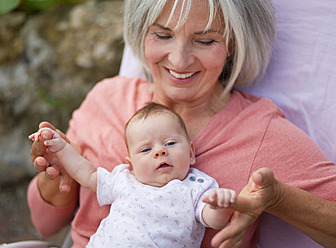 Germany, Bavaria, Woman with grandchild sitting in lawn chair, smiling - HSIYF000006