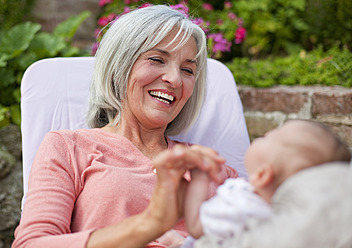 Germany, Bavaria, Woman with grandchild sitting in lawn chair, smiling - HSIYF000008