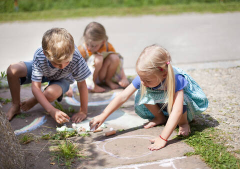 Deutschland, Bayern, Gruppe von Kindern, die mit Kreide auf einem Gehweg zeichnen, lizenzfreies Stockfoto