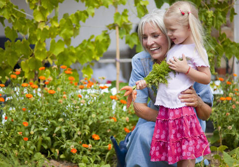 Deutschland, Bayern, Reife Frau mit Mädchen im Garten, lizenzfreies Stockfoto