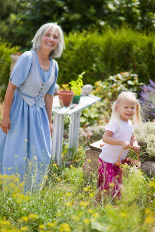 Deutschland, Bayern, Reife Frau mit Mädchen im Garten, lizenzfreies Stockfoto