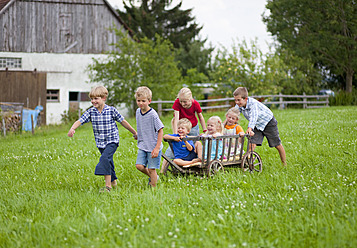 Deutschland, Bayern, Gruppe von Kindern, die mit einem Handwagen vor einem Bauernhaus spielen - HSIYF000027