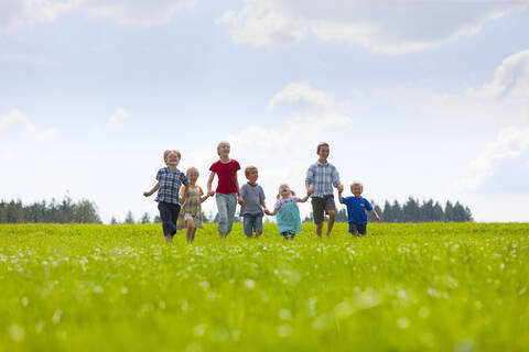 Deutschland, Bayern, Gruppe von Kindern, die über eine Wiese laufen, lizenzfreies Stockfoto