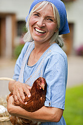 Deutschland, Bayern, Ältere Frau mit Korb mit frischen Eiern und Hühnern - HSIYF000046