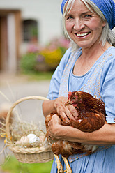Deutschland, Bayern, Ältere Frau mit Korb mit frischen Eiern und Hühnern - HSIYF000047