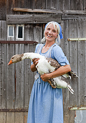 Germany, Bavaria, Mature woman with goose on farm - HSIYF000070