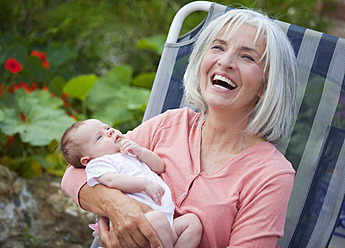 Germany, Bavaria, Woman with grandchild sitting in lawn chair, smiling - HSIYF000076