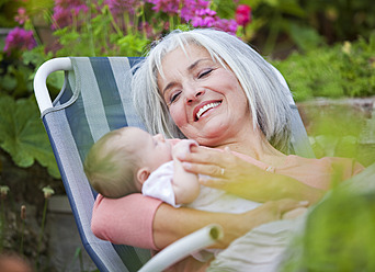 Germany, Bavaria, Woman with grandchild sitting in lawn chair, smiling - HSIYF000077