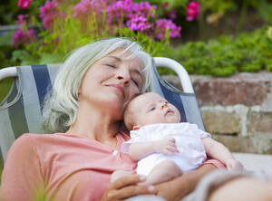 Germany, Bavaria, Woman with grandchild relaxing in lawn chair, smiling - HSIYF000078