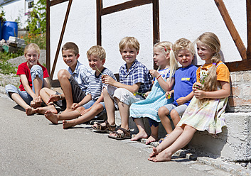 Deutschland, Bayern, Gruppe von Kindern, die vor einem kleinen Haus sitzen - HSIYF000116