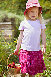 Germany, Bavaria, Girl with basket of strawberries in garden - HSIYF000119