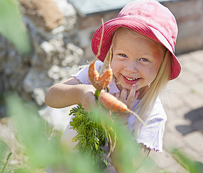 Deutschland, Bayern, Mädchen pflückt Möhren im Garten - HSIYF000126