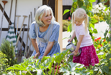 Germany, Bavaria, Mature woman and girl in graden caring for plants - HSIYF000132