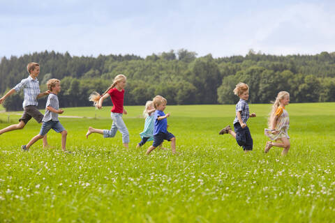 Germany, Bavaria, Group of children running through meadow stock photo