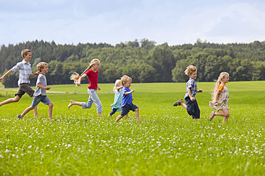 Deutschland, Bayern, Gruppe von Kindern, die über eine Wiese laufen - HSIYF000140