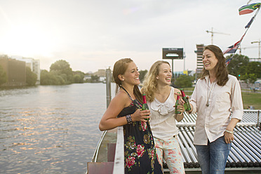 Germany, Berlin, Young students enjoying drink at Spreeufer River - FKF000064