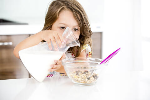 Deutschland, Mädchen gießt Milch ins Müsli, lizenzfreies Stockfoto