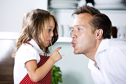 Deutschland, Tochter isst Nudeln mit Vater in der Küche - RFF000053