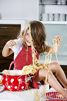Deutschland, Mädchen spielt mit Spaghetti auf Küchenarbeitsplatte - RFF000068
