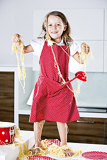 Deutschland, Mädchen spielt mit Spaghetti auf Küchenarbeitsplatte - RFF000070