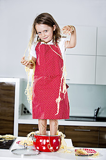 Deutschland, Mädchen spielt mit Spaghetti auf Küchenarbeitsplatte - RFF000071