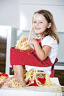 Deutschland, Mädchen spielt mit Spaghetti auf Küchenarbeitsplatte - RFF000072