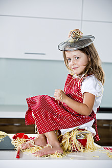 Deutschland, Mädchen spielt mit Spaghetti auf Küchenarbeitsplatte - RFF000075