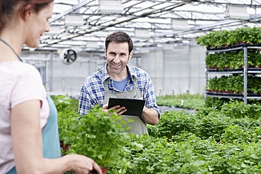 Germany, Bavaria, Munich, Mature man and woman with clip board in greenhouse - RREF000024