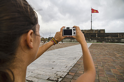 Vietnam, Hue, Junge Frau beim Fotografieren der Zitadelle von Hue - MBEF000521