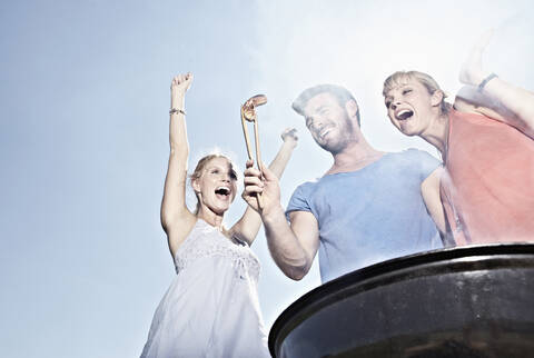 Deutschland, Köln, Männer und Frauen versammelt um Grill, lizenzfreies Stockfoto