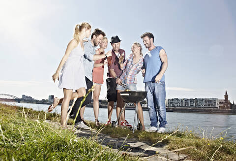 Deutschland, Köln, Gruppe von Menschen um Grill versammelt, lizenzfreies Stockfoto