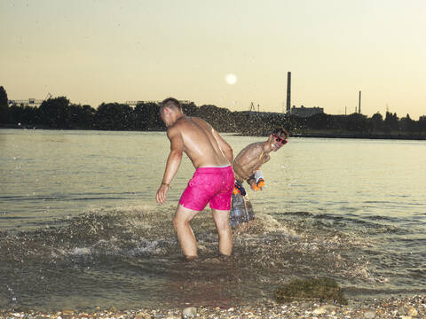 Deutschland, Düsseldorf, Junge Freunde spielen im Wasser, lizenzfreies Stockfoto