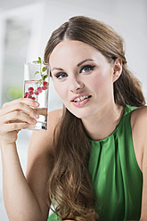Deutschland, Junge Frau hält ein Glas Wasser mit Beeren - RFMYF000018