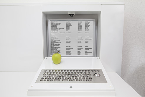 Germany, Apple on keyboard and screen installed in furniture - FMKYF000249