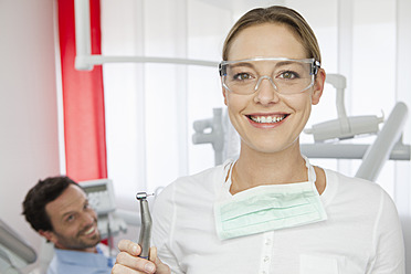 Germany, Dentist with safety glasses, patient in background - FMKYF000254