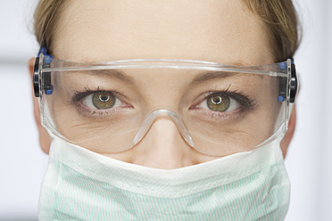 Germany, Dentist with safety glasses and surgical mask in dental office - FMKYF000256