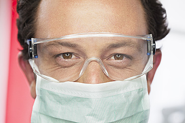 Germany, Dentist with safety glasses and surgical mask in dental office - FMKYF000257