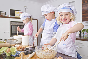 Germany, Girls and boy preparing dough and baking cup cake in kitchen - FKF000088