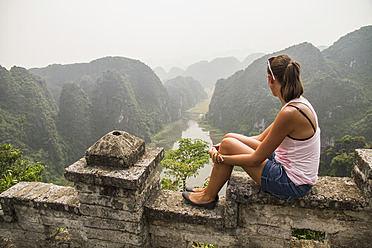 Vietnam, Ninh Binh, Junger Tourist mit Blick auf das Tom Coc Tal - MBEF000530