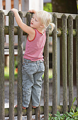 Deutschland, Mädchen steht auf einem Spielplatz am Zaun - TCF002942