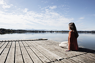 Germany, Bavaria, Young woman sitting on jetty - RBF001052