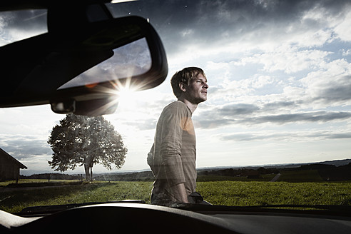 Deutschland, Bayern, Mittlerer erwachsener Mann stehend am Auto - RBF001090