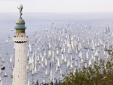 Italy, Sailing boats racing across Gulf of Trieste in annual boat race with lighthouse in foreground - BSCF000175