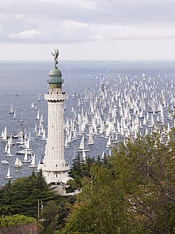 Italy, Sailing boats racing across Gulf of Trieste in annual boat race with lighthouse in foreground - BSCF000174