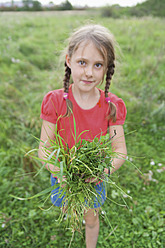 Europe, Germany, Munich, Girl holding bundle of grass at Naturindianer - TCF002960